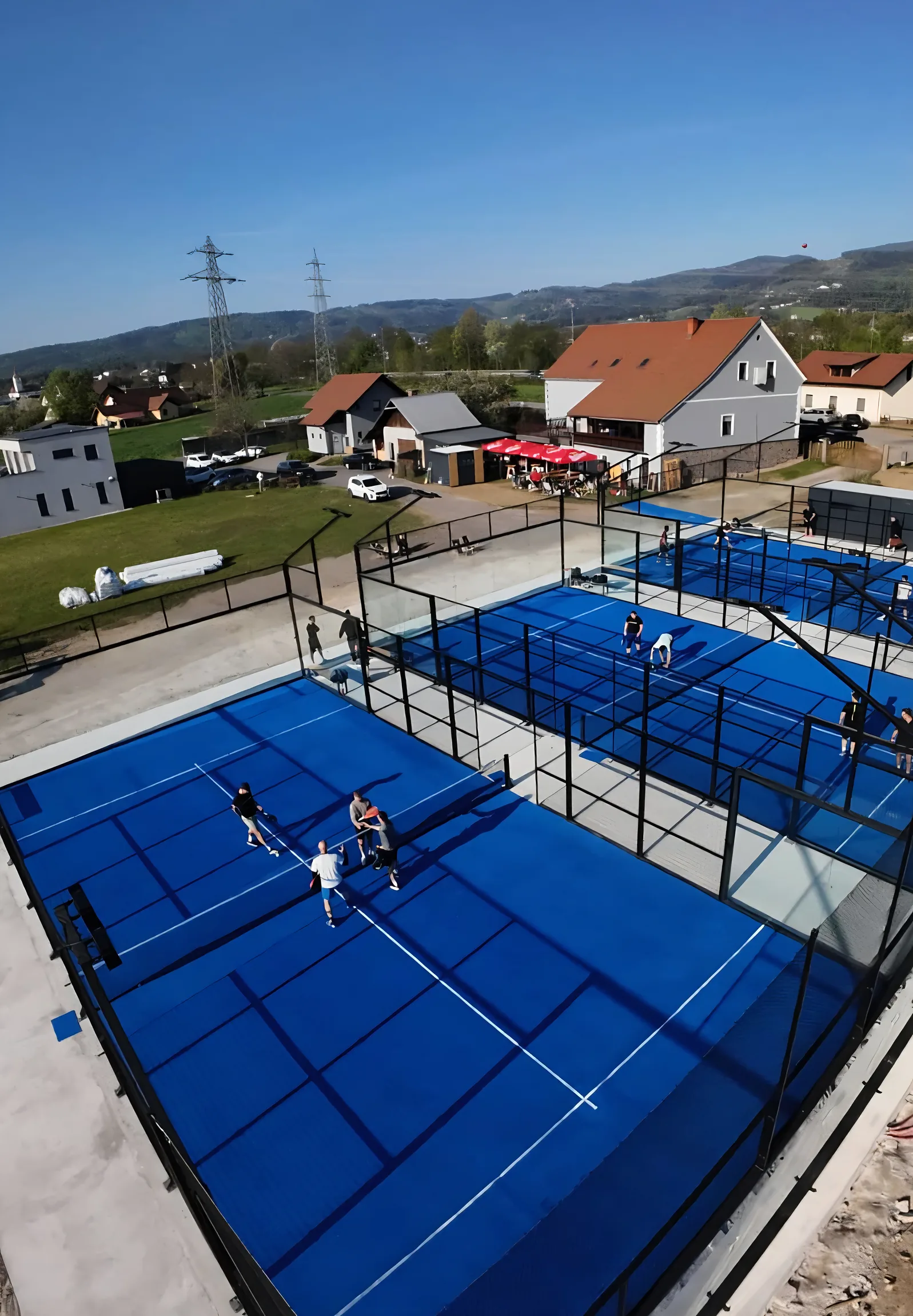 Pogled iz zraka na tri modra padel igrišča Padel Baza v Bohovi med igro